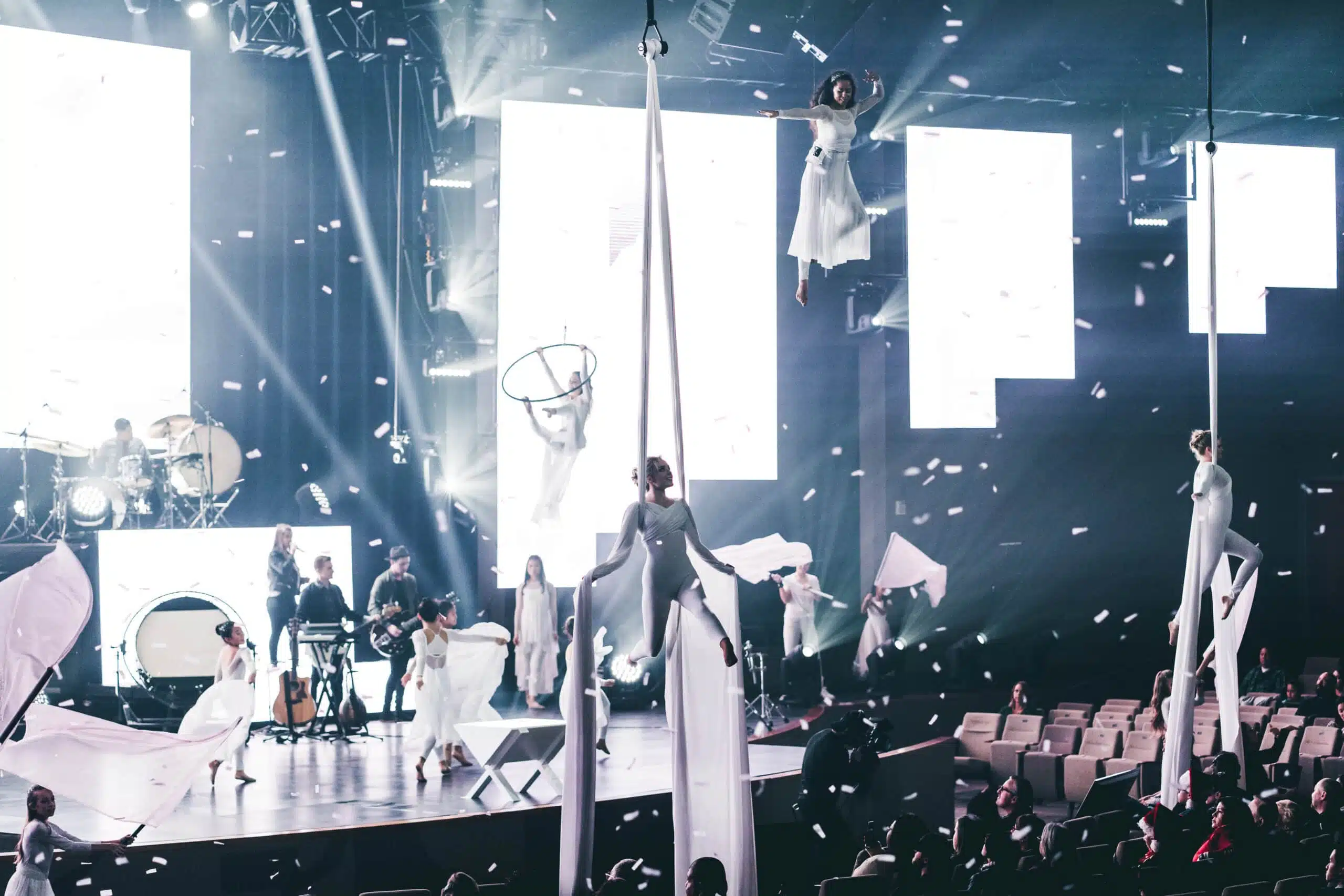 a stage with silks suspended from the ceiling and silk dancers performing on them